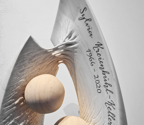Grabsteinkunst mit elliptischer Form, symbolischen Kugeln und organischer Textur, handgefertigt von der Bildhauerei Sini in Grenchen (Region Solothurn und Bern), Detailansicht