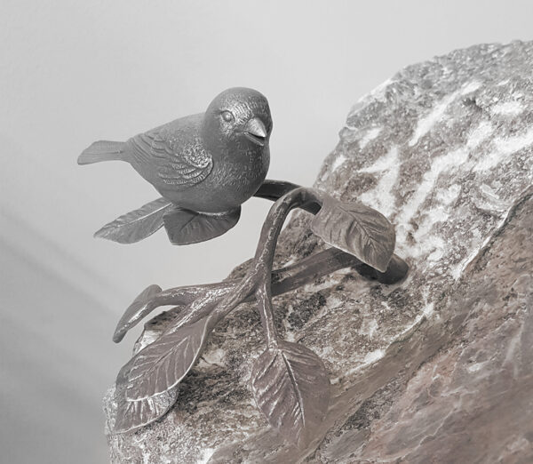 Grabstein mit Vogel aus Metall der auf einem Ast mit Blättern sitzt, handgefertigt von der Bildhauerei Sini in der Region Solothurn und Bern