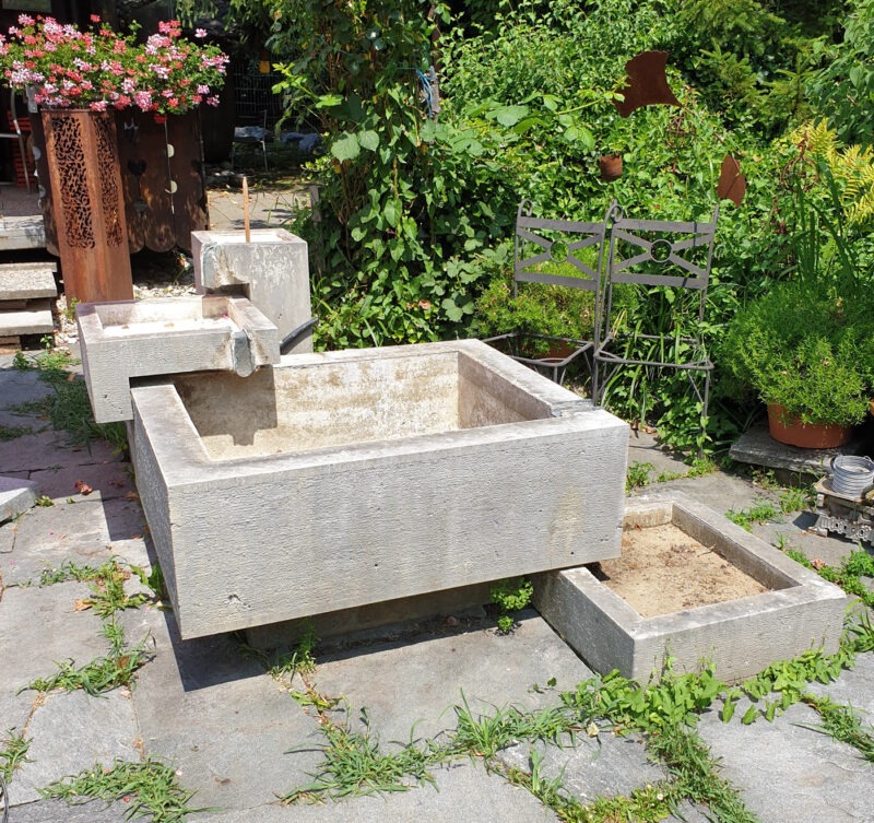Handgefertigter Steinbrunnen der Bildhauerei Sini in Grenchen vor der Reinigung. Die Bildhauerei Sini in Grenchen übernimmt professionelle Reinigungen von Steinobjekten und Steinbrunnen.